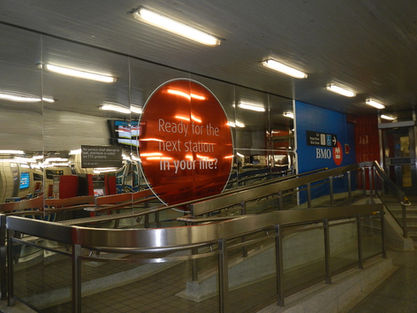 Window decal printed by Category 5 for the BMO bank in the underground path in Toronto, Ontario leading to a subway station. The decal is a red circle and has text which reads "Ready for the next station in your time?".