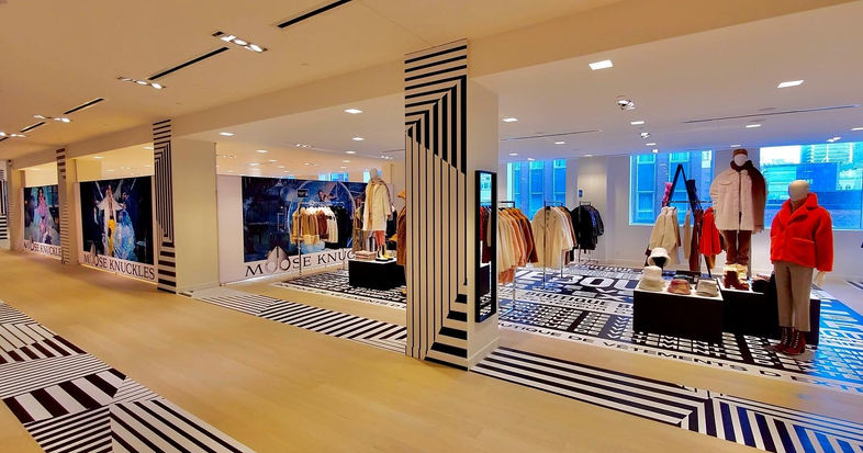 Retail interior floor and pillar decals for Holt Renfrew at their Oglivy location in Montreal. The design of the vinyl print features black and white striped patterns, going in different directions.