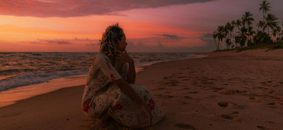 A woman sitting on the beach at sunset in reflection