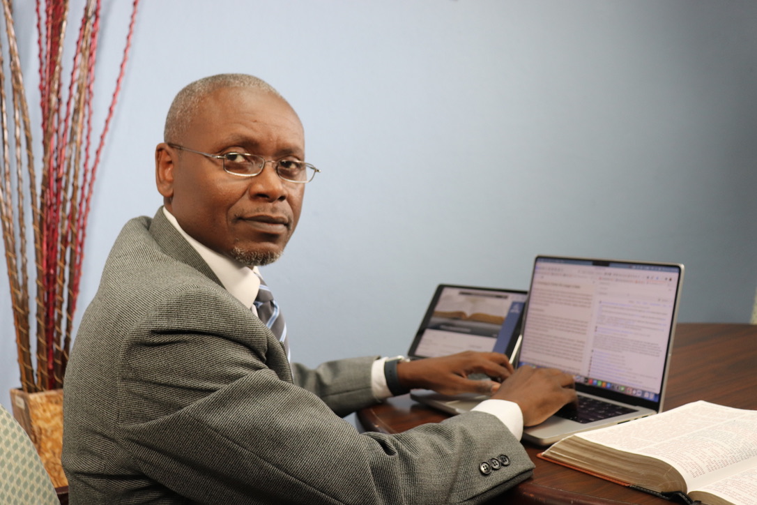 Lynden Williams studying with computers and an open Bible