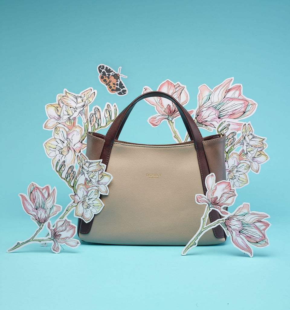 Photo of a handbag surrounded by 3D painted flowers and a butterfly