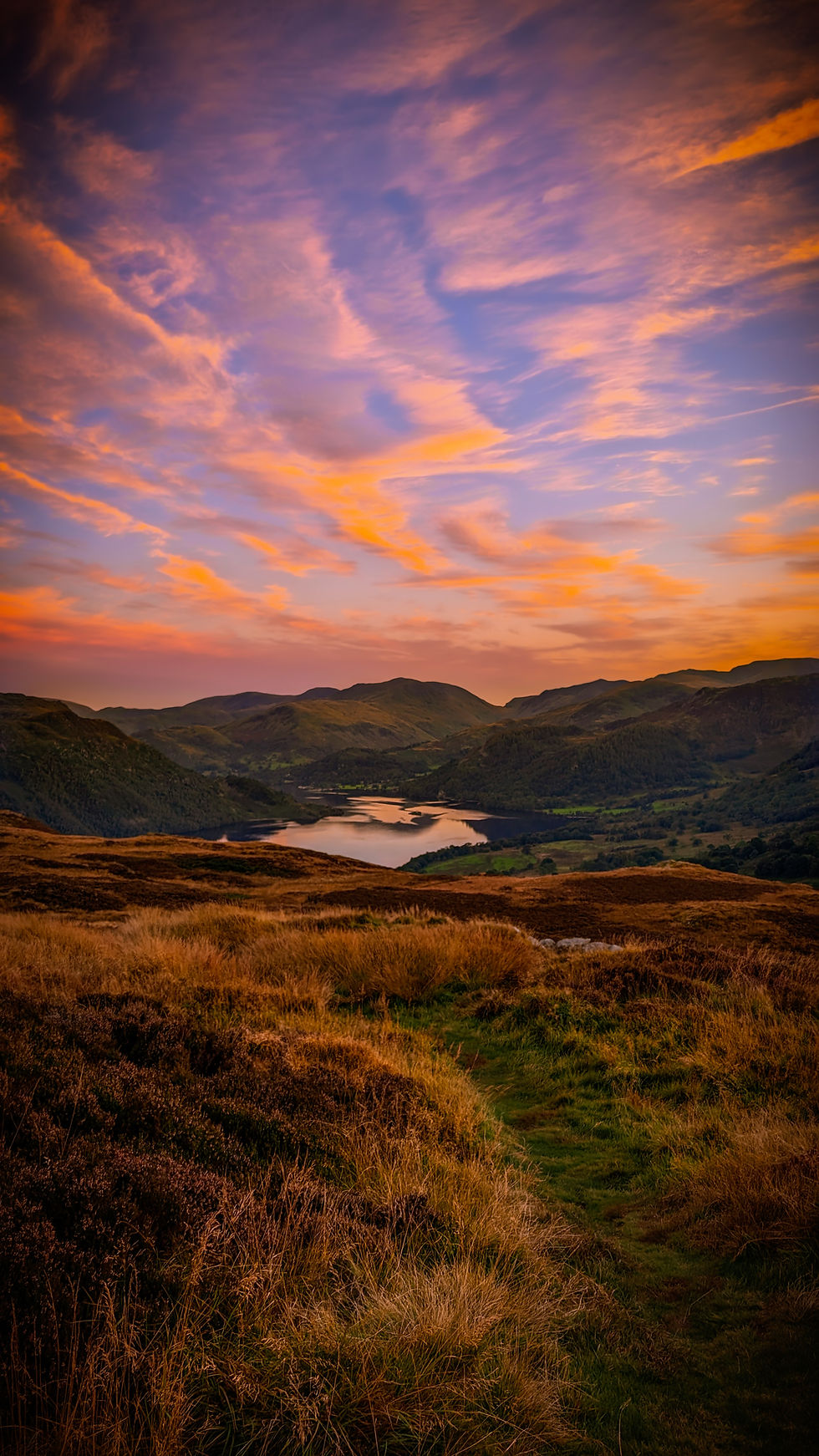 pink sunset over lake surrounded by mountains