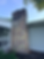 - Chimney with damaged multicolored stone veneer and exposed masonry beside a front porch.