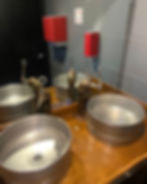 Custom keg-style sinks with industrial pipe faucets in a commercial bathroom by Asmann Corp.