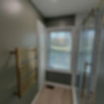 Finished bathroom with green walls, brass heated towel rack, wood-look flooring and glass walk-in shower.