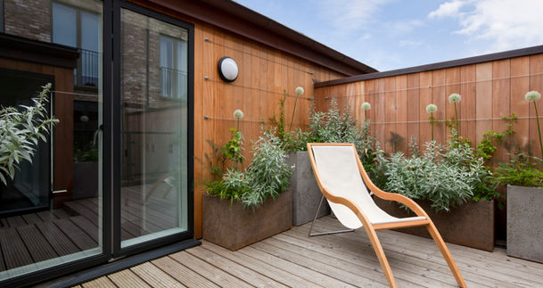 Terrasse chic sur le toit avec transat en bois et plantes vertes.
