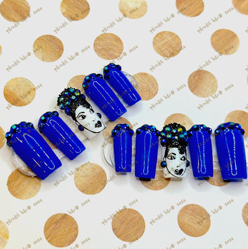 Electric blue press-on nails with rhinestone accents and a hand-painted design of a little girl in the middle.