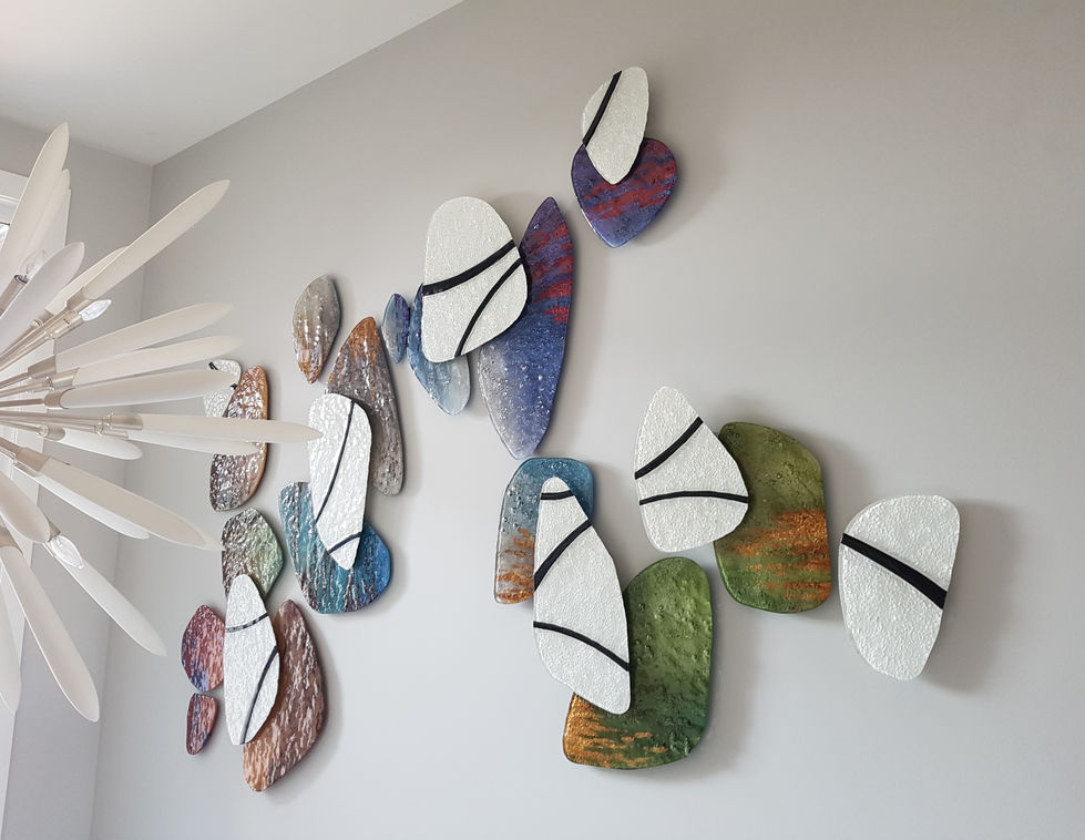 This beautiful glass art wall sculpture works with texture, soft shapes and a full spectrum of colours in earthtones that move into jewel tones. the second layer is white with black lines that create a circle geometric design over the sculpture.