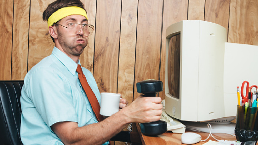 man in office lifting weight at computer