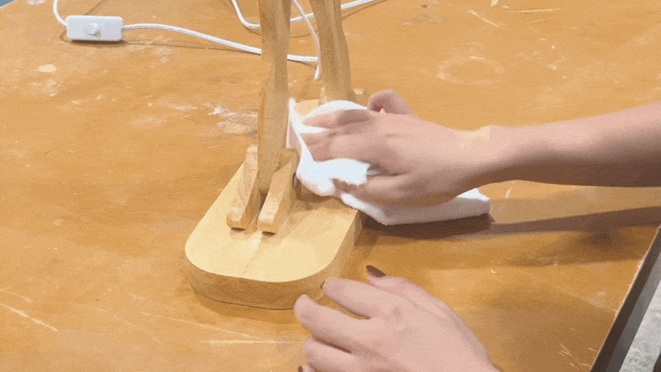 Wiping off the excess wood wax with a cloth, leaving the wooden surface smooth and polished.