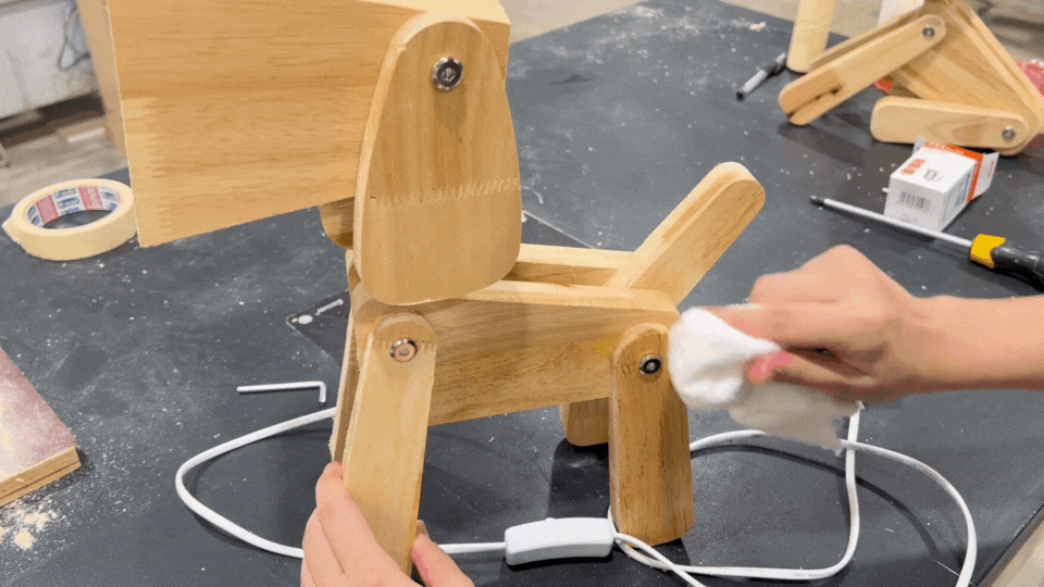 Wiping off the excess wood wax with a cloth, leaving the wooden surface smooth and polished.