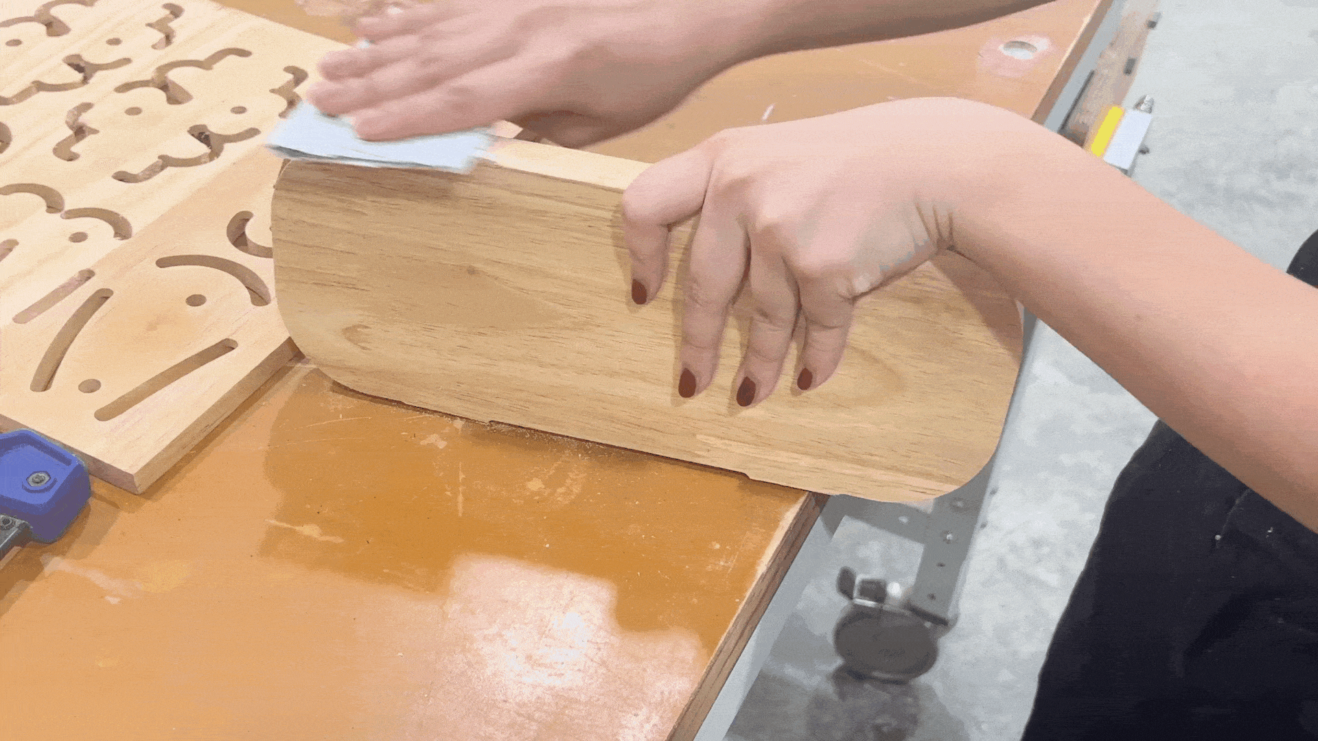 Sanding a wooden piece by hand to smoothen the surface for assembly.