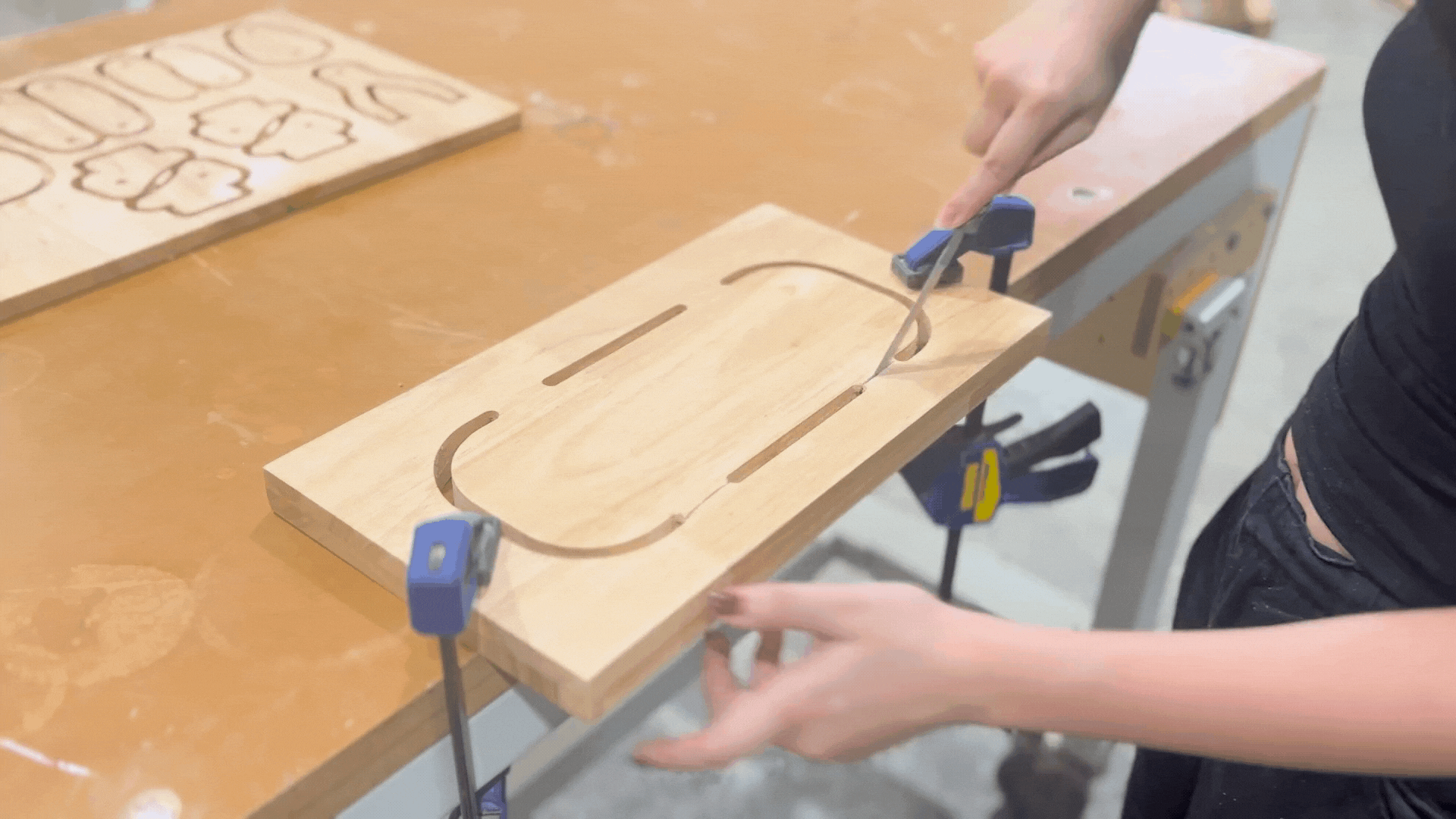 Person using a hand saw to cut a wooden board for crafting a lamp.