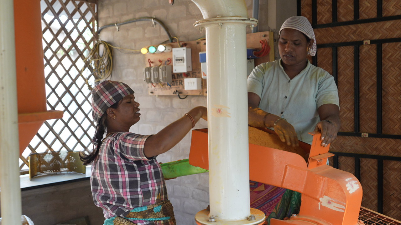 Women working on a millet processing machine