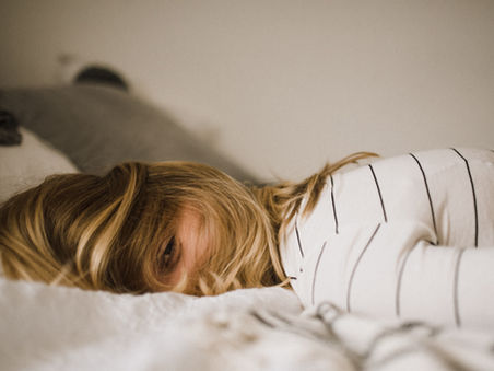 A woman in a striped top resting her head on white bedding.