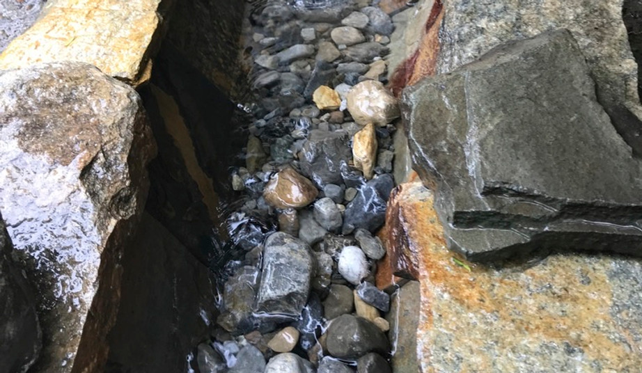 Water flowing through a narrow stone-lined channel. 