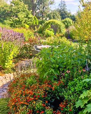 Circular paver sitting area with lush planting and a vine-covered moon gate.