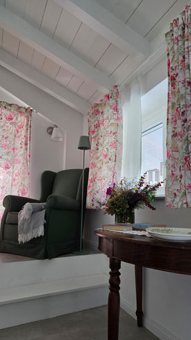 Camera di bed & breakfast, floreale, focus su letto, poltrona e spazio luminoso. / Bed and breakfast room, floral theme, focusing on the bed, armchair and bright space.