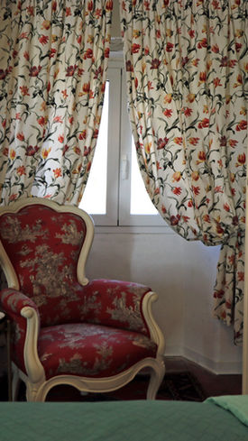 Camera di bed & breakfast, focus su letto, poltrona e spazio luminoso. / Bed and breakfast room, theme, focusing on the bed, armchair and bright space.