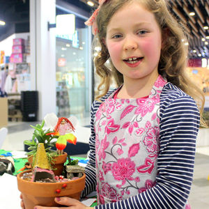 Young Girl holds a fairy garden she has made in a shopping centre