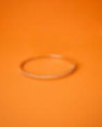 The Rose Diamond Whisper Bangle showcased on an orange background