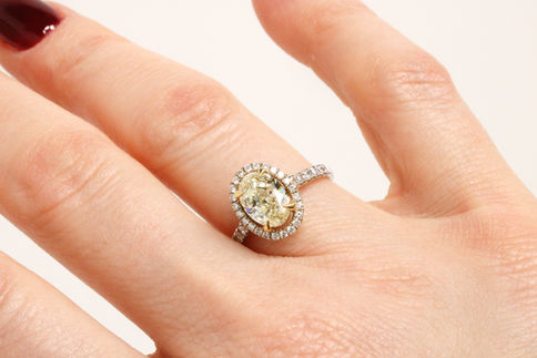 A close look on the Sunburst Halo Yellow Oval Engagement Ring no a model's hand