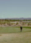 Golfer walking on the green with two golf clubs in hand