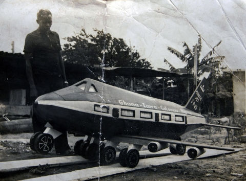 Une photographie (archive historique de famille) qui présente Kane Kwei devant l'un de ses cercueils artistiques..