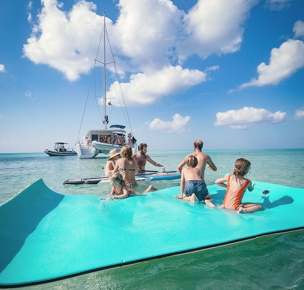 Family having fun with kids in a mate float in el Cielo sandbar Cozumel with the Cozumel Windseekers Catamaran in the background