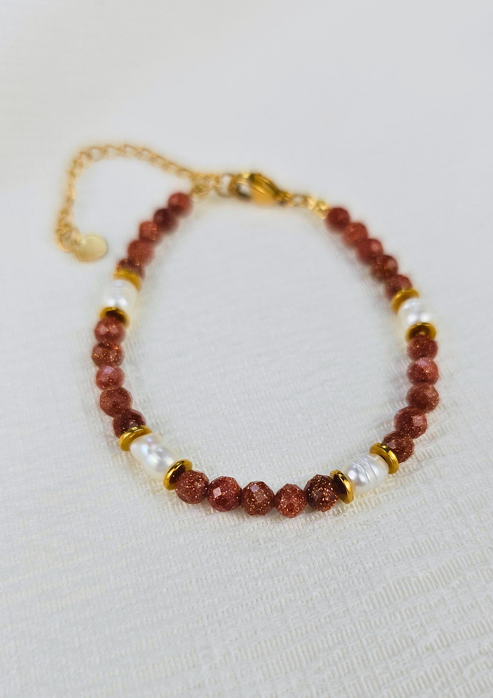 Detailaufnahme des Armbands mit facettiertem goldenem Sandstein, schimmernden Süsswasserperlen und hochwertigem Edelstahl