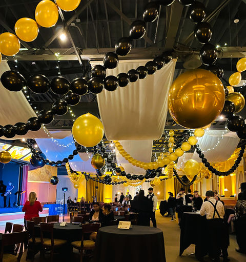 room decorated with hanging black, gold and white balloons and balloon  links 