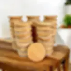 Multiple stacks of round bamboo jar lids on a wooden table.