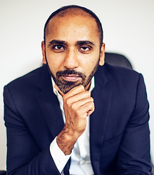 Photo of Moiz Ali, founder of Native. He's a brown man with short dark hair and a wellgroomed beard. He's wearing a nice navy suit and has his hand up to his chin.