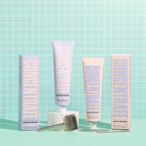 We Are Concentrate No Added Water Conditioner – A bathroom setting with pale blue tubes and boxes of "We Are Concentrate" haircare products, including conditioner and shampoo.
