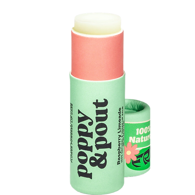 A biodegradable paper tube of lip balm with a pastel green base and a coral cap, labeled Poppy & Pout in Raspberry Limeade flavor, with a floral design indicating a vegan product.