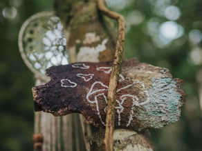 A serene detail from Lunita Jungle in Mexico, showcasing a crafted wooden decoration adorned with nature-inspired symbols, capturing the peaceful essence of the retreat center.
