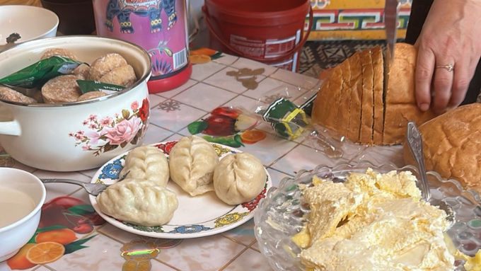 モンゴルの遊牧民のゲルの中で、ボーズ(蒸し餃子)やパン・乳製品が並ぶ食卓