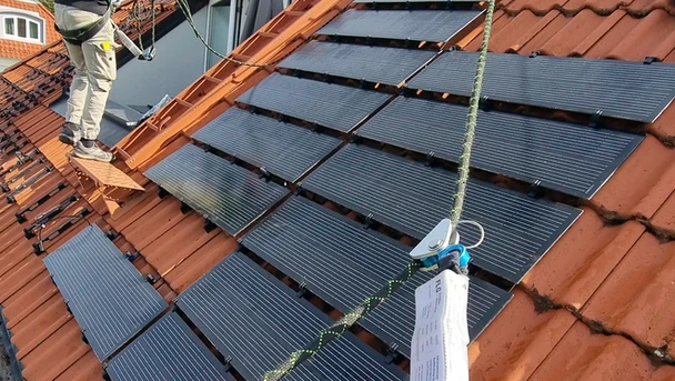 Techniker installieren Solarmodule auf Ziegeldach
