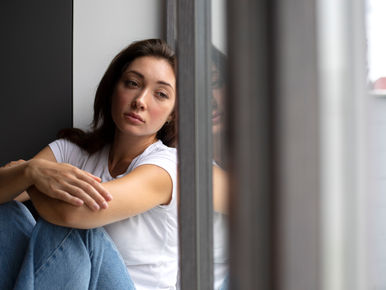 Mulher triste olhando pra janela