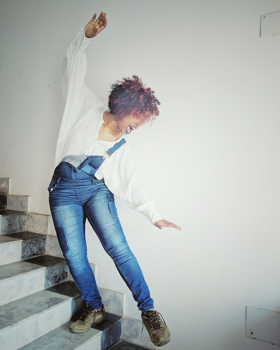 Self portrait of a woman with curly hair wearing a white shirt and a jumpsuite