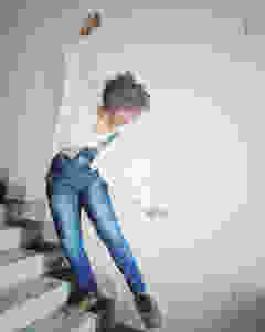 Self portrait of a woman with curly hair wearing a white shirt and a jumpsuite