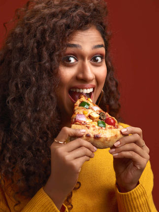 Pizza Commercial photography campaign | Female indian model having a big slice of mix veg pizza
