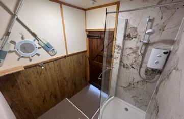 Compact bathroom with shower, wood paneling, porthole