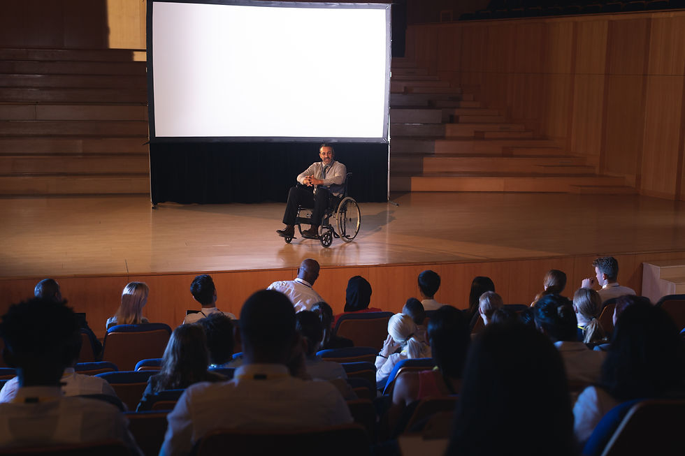 An image of a group of people at an event where a man in a wheelchair is leading a presentation