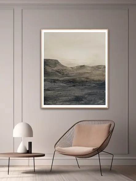 Tableau de paysage de montagnes dans un salon beige avec un fauteuil design