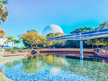 Spaceship Earth in Epcot behind trees, and pond, and the monorail line.