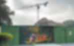 At Disney's Animal Kingdom: a large crane and dirt pile is visible over a construction wall with a large artists rendering of the Madrigal family from Disney's Encanto.