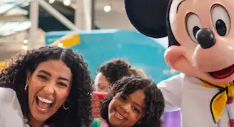 A family taking a picture with Mickey Mouse