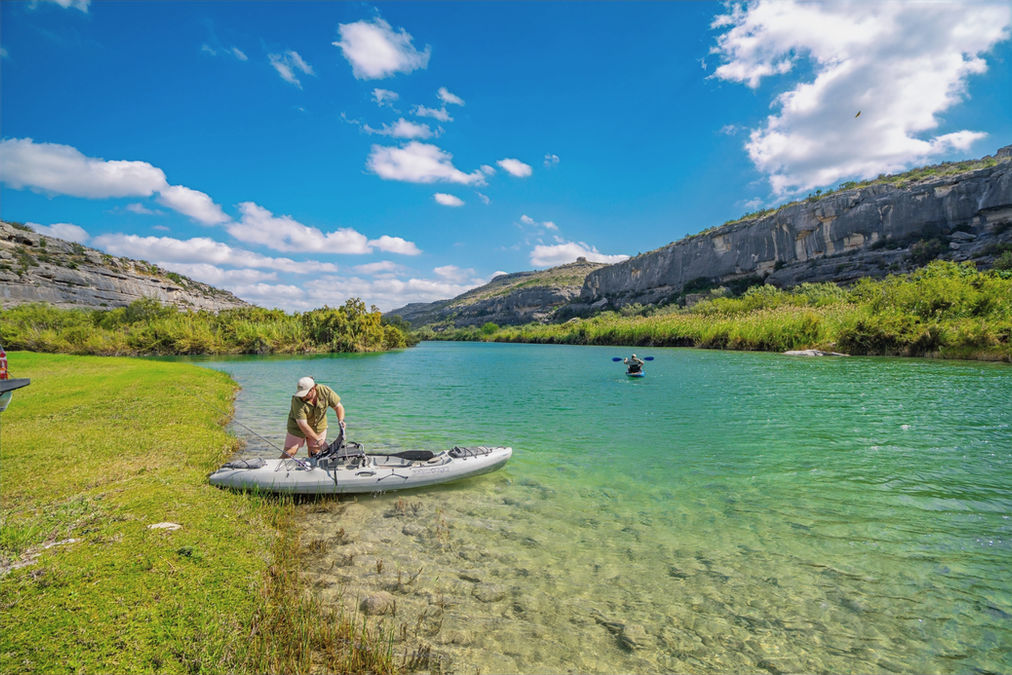 a man climbing into his kayak for a fishing day on the river