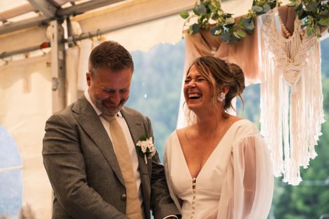 a bride laughs heartily and holds hands with her groom